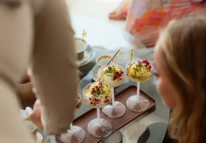 Tre skålar med bastani sonnati, en persisk glassdessert, toppad med granatäppelkärnor och pistasch.