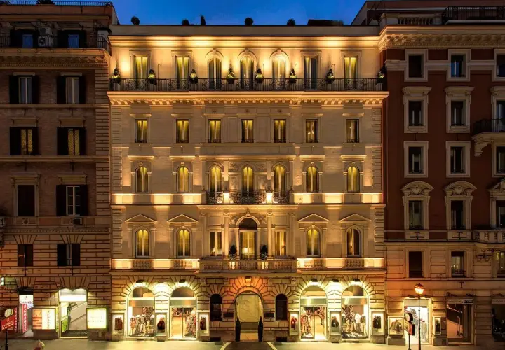 Edificio illuminato di notte, con negozi al piano terra, nel quartiere Esquilino a Roma.