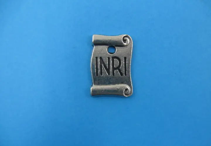 Metalowy zwój z napisem INRI, symbolizujący tabliczkę z krzyża.