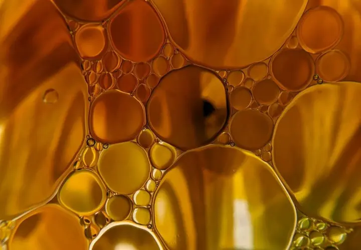 Gotas doradas y ámbar flotan juntas, creando un patrón hipnótico que te hace soñar con aceite.