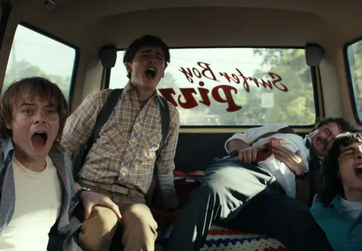 Czterech przerażonych przyjaciół z Stranger Things 4 krzyczy w vanie, gdy przejeżdżają obok Surfer Boy Pizza.