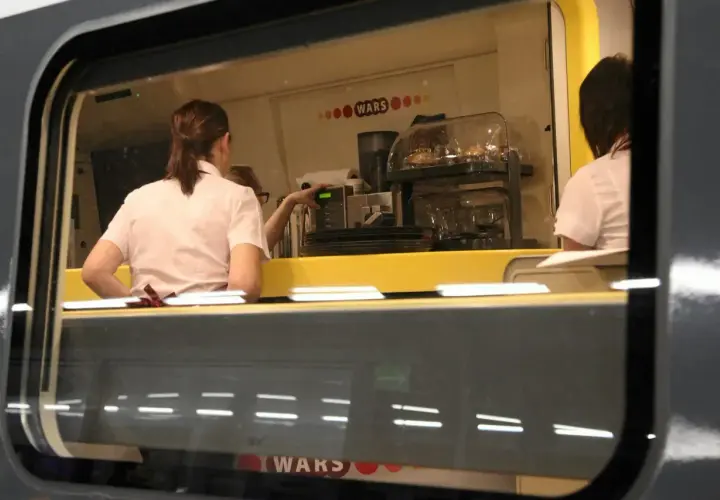 Wnętrze wagonu restauracyjnego z obsługą przygotowującą napoje.