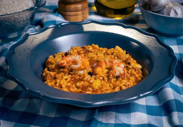 Un plato de paella mixta con gambas y arroz dorado, listo para disfrutar.