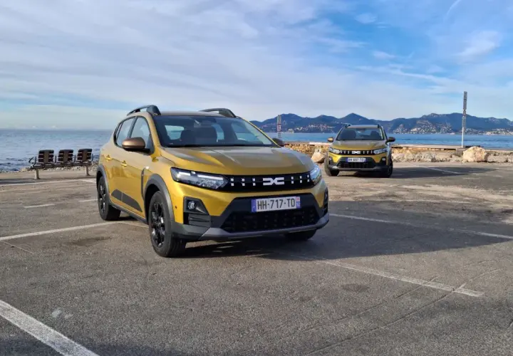 Dwa złote Dacia Sandero Stepway na tle morza i gór. Dwa modele, różne silniki, gotowe na przygodę.