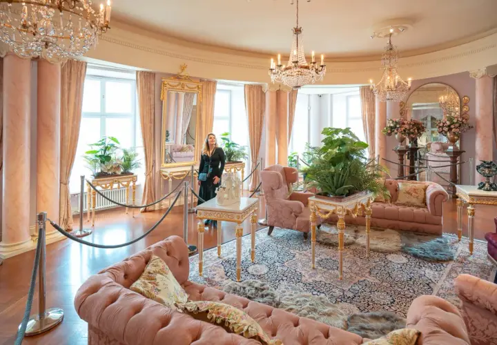 Elegancki salon z różowymi sofami i kryształowymi żyrandolami. Marzenie o noclegu w zamku staje się rzeczywistością.