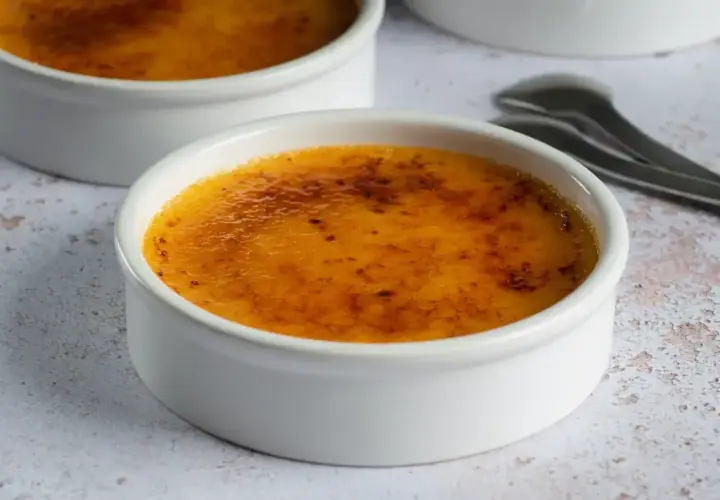 Dwa białe naczynia z pyszną, skarmelizowaną górą. Idealna crema catalana, gotowa do rozkoszowania się.