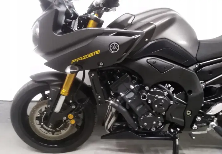 Ciemnoszary motocykl Yamaha FZ8 z żółtym napisem "FAZER" na owiewce. Widoczny przedni widelec i koło.