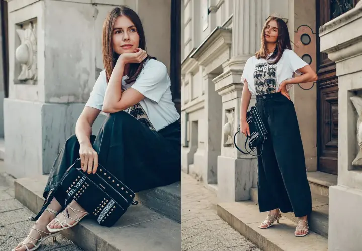 Kobieta w luźnych spodniach i t-shircie z motywem zwierzęcym, z torebką Desigual ozdobioną ćwiekami.