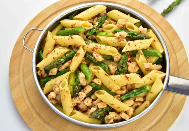 Penne z kurczakiem i szparagami, posypane papryką. Pyszne danie na obiad.