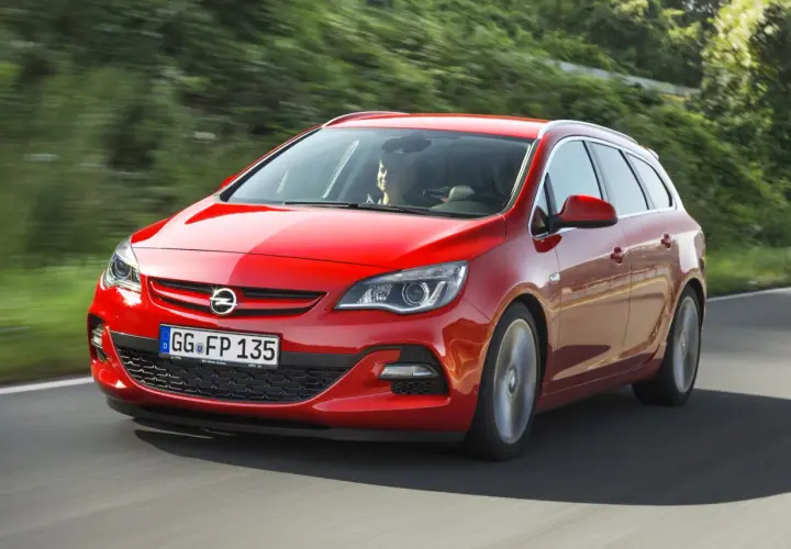 Czerwony Opel Astra J 1.4 Turbo 140 KM na drodze. Kierowca zadowolony, auto w ruchu.