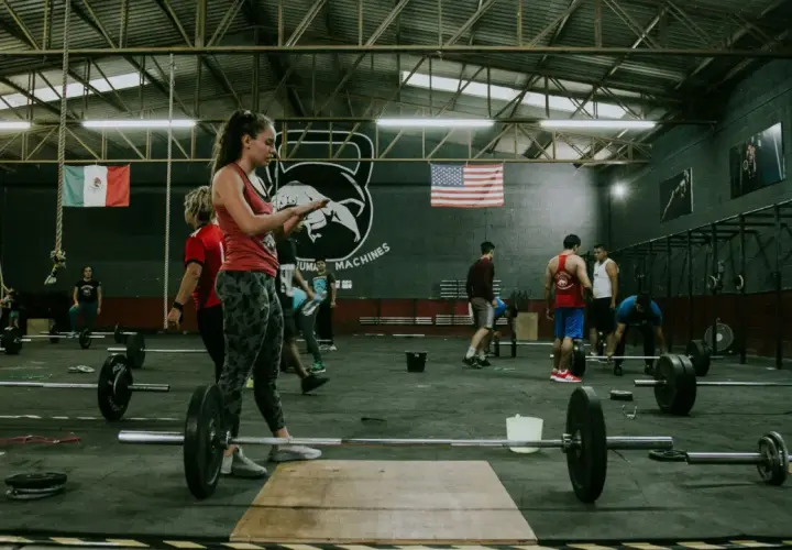Ludzie ćwiczący CrossFit w siłowni z ciężarami i flagami Meksyku i USA.