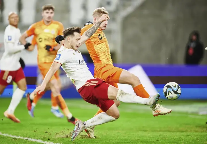 Piłkarz Zagłębia Lubin walczy o piłkę z zawodnikiem ŁKS Łódź. Intensywna akcja na boisku.