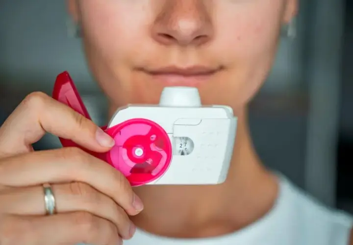 Eine Person hält einen Inhalator, bereit zum Inhalieren.