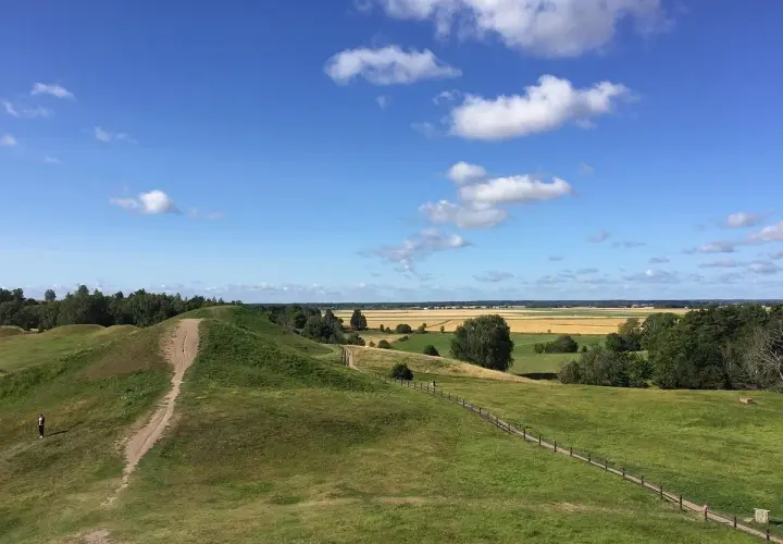Gröna kullar och en stig leder till en fantastisk utsikt över fält och skog. Upplev Uppsala från ovan!