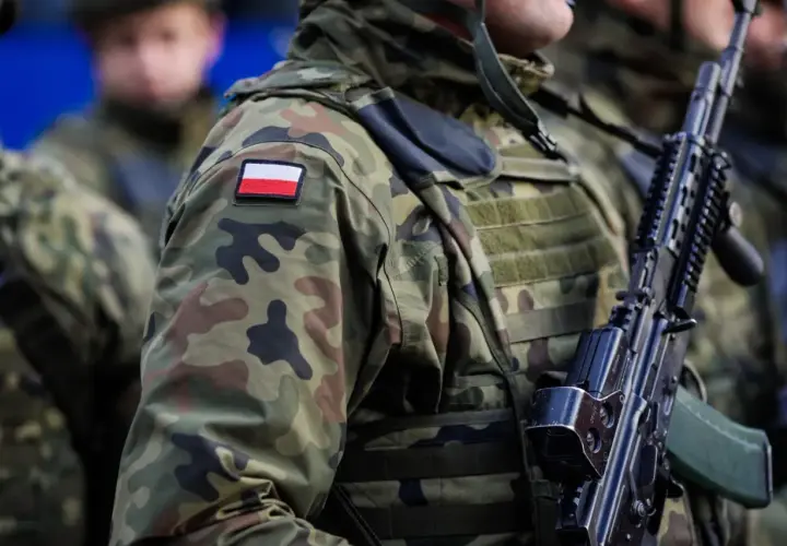 Żołnierze w kamuflażu, z polską flagą na ramieniu, gotowi do mobilizacji. Broń w rękach, czujność na twarzach.