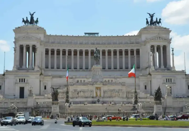 Monumentalny budynek na Piazza Venezia w Rzymie, z rzeźbami i flagami Włoch.