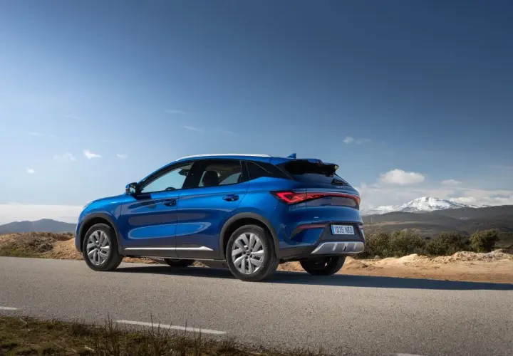 Un BYD Atto 3 azul en una carretera rural, listo para una prueba de manejo con montañas nevadas al fondo.