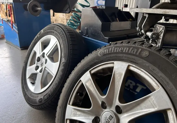 Dwa aluminiowe felgi z oponami Continental i Michelin, gotowe do prostowania felgi aluminiowej w warsztacie.