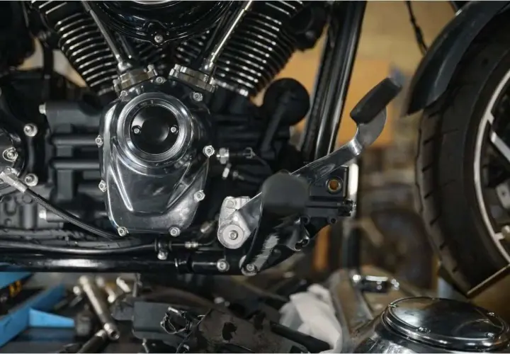 Detalle del motor de una motocicleta, mostrando el embrague y la palanca de cambios.