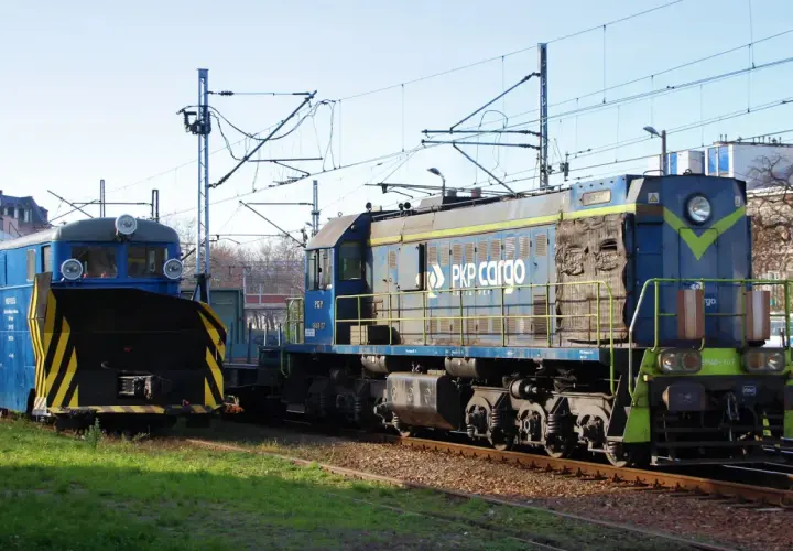 Dwie lokomotywy PKP Cargo, w tym jedna z pługiem śnieżnym, stoją na torach. Lokomotywa tem2 jest niebieska z żółtymi pasami.