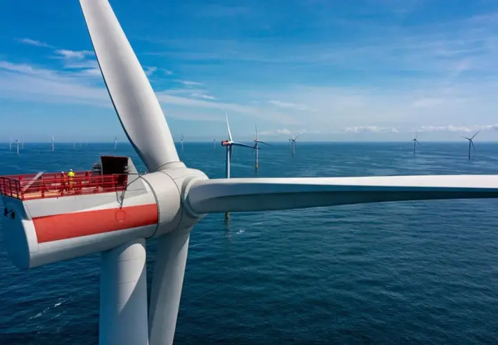 Wielka turbina wiatrowa na morzu, część projektu Baltica 2, z pracownikami na platformie. W tle widać kolejne morskie farmy wiatrowe.