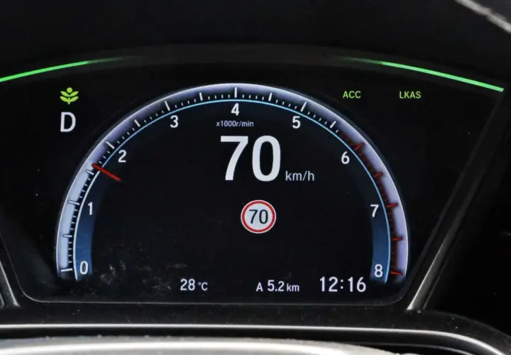 Cyfrowy prędkościomierz samochodu pokazuje 70 km/h, obok wskaźnik temperatury i zegar.