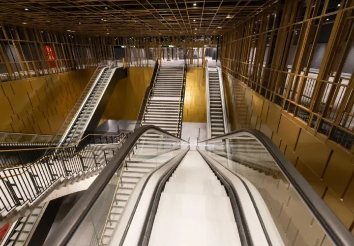 Interno moderno della **metro Cavour Roma**, con scale mobili e gradinate che conducono ai binari, pareti dorate e soffitto a griglia.