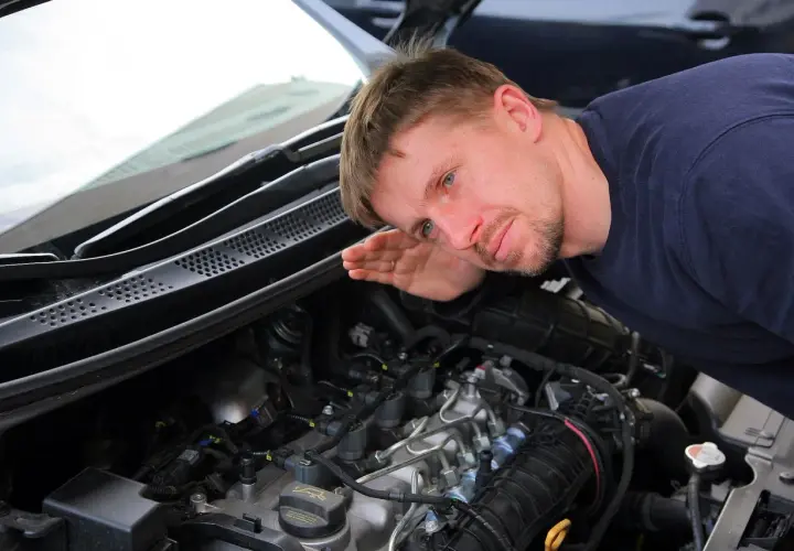 Mechanik nasłuchuje pracy silnika, skupiając się na kolektorze.