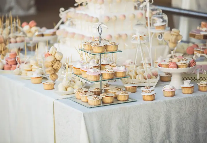 Un magnifique buffet de mariage avec une idée de présentation de desserts : cupcakes, macarons, cake pops et une pièce montée.