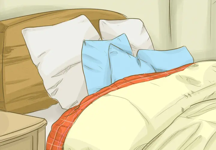 Cozy bed with pillows and a plaid blanket, perfect for learning how to get warmer in bed.