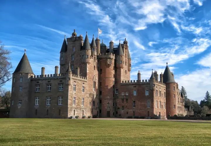 Castillo escocés con torres cónicas y un gran césped verde, perfecto para tus viajes a Escocia.