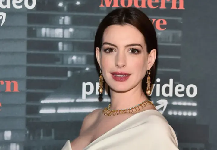 Anne Hathaway, której wiek jest często przedmiotem dyskusji, prezentuje się olśniewająco w złotej biżuterii na tle logo Amazon Prime Video.