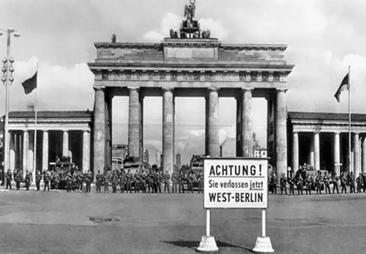 Brandenburger Tor, Soldaten und Panzer stehen Spalier. Ein Schild warnt: "ACHTUNG! Sie verlassen jetzt WEST-BERLIN". Ein Symbol des kalten Krieges.