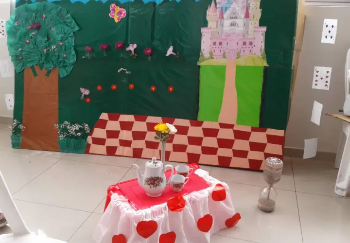 Escenario de manualidades alicia en el país de las maravillas con castillo, árbol, mesa de té y reloj de arena.