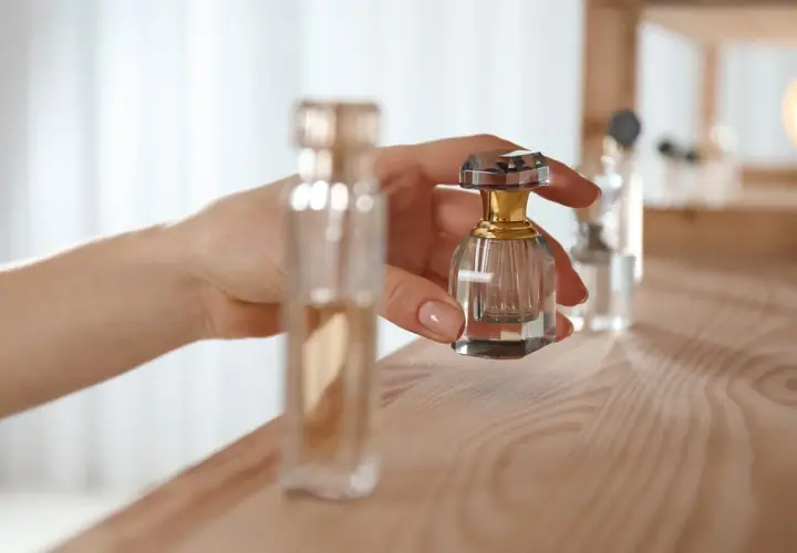 Dłoń trzyma małą, kryształową buteleczkę perfum. Proces maceracji perfum wymaga cierpliwości.