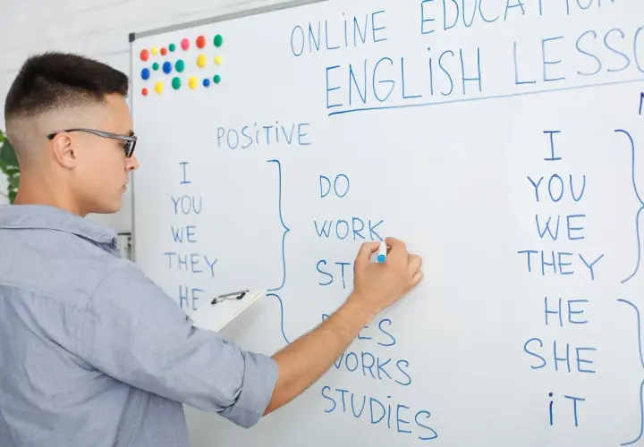 Chłopak pisze na tablicy "ONLINE ENGLISH LESSON". Uczy się, ile jest słów w języku angielskim, tworząc zdania.