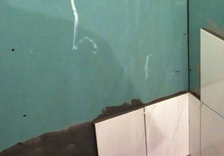 Angolo di una stanza con piastrelle su cartongesso in fase di posa. La parete verde è pronta per essere rivestita.