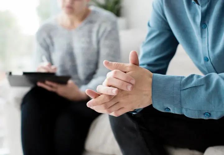 Due mani intrecciate in un colloquio, forse per affrontare la ruminazione mentale e valutare l'uso di farmaci.