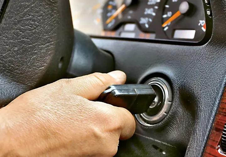 Dłoń przekręca kluczyk w stacyjce. Auto odpala i gaśnie, co sugeruje problem z zapłonem lub paliwem.