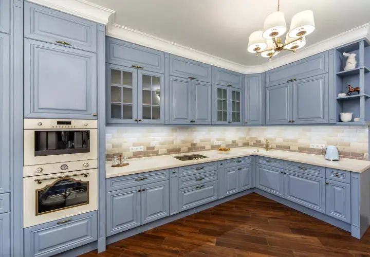 Cucina moderna con mobili blu polvere, un'idea per cambiare colore alla cucina. Pavimento in legno scuro e illuminazione soffusa.