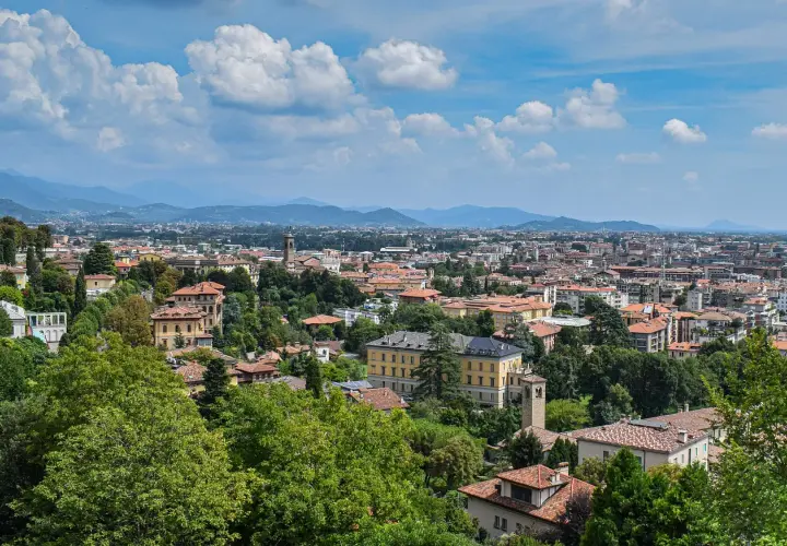 Widok na Bergamo z licznymi dachami i zielenią, idealne miejsce na loty do Bergamo.
