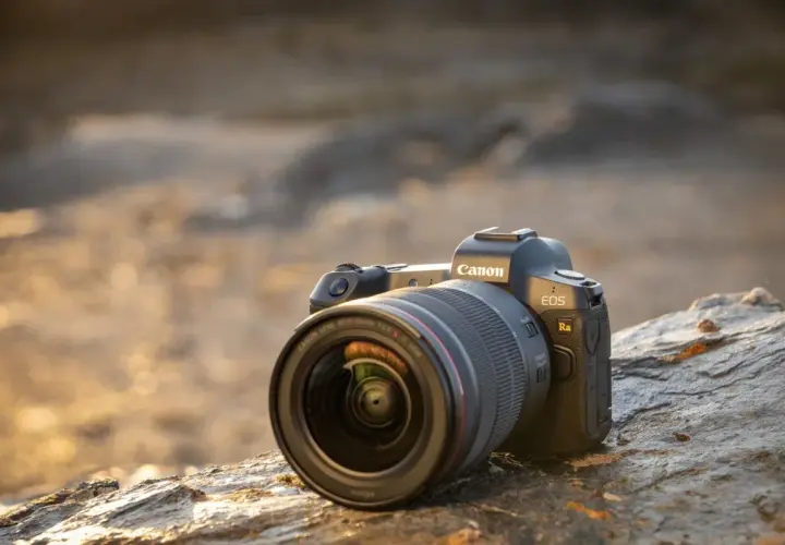 Profesjonalny aparat do astrofotografii Canon EOS Ra z obiektywem RF 15-35mm f/2.8 L IS USM leży na kamieniu.