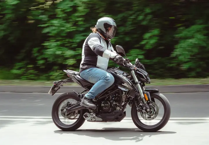 Mężczyzna w kasku jedzie czarnym motocyklem. Idealny motor na kat B, by poczuć wolność na drodze.