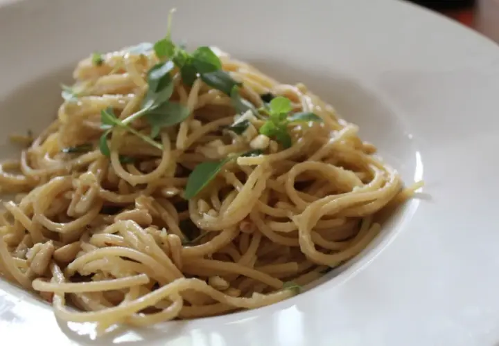 Deliciosa pasta con piñones y hierbas frescas, servida en un plato blanco.