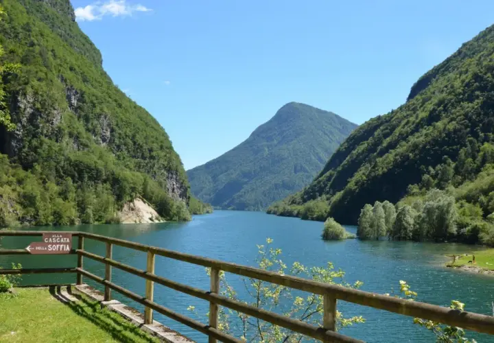Il lago del Mis, incastonato tra montagne verdi e rigogliose, offre uno spettacolo mozzafiato con le sue acque azzurre e il cielo limpido.