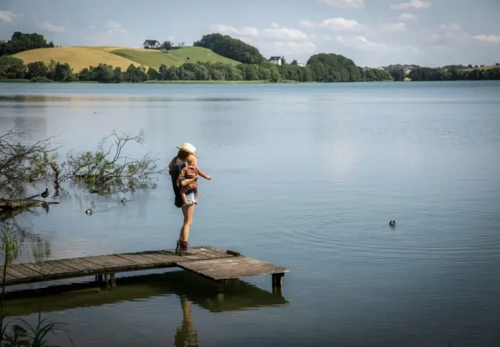 Kobieta z dzieckiem na rękach na pomoście, podziwia krajobraz. Sielski widok, jak ze szwajcarskiej wsi, ale to Kaszuby.