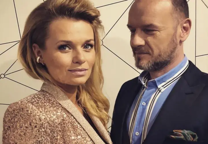 Emilia Komarnicka z pierwszym mężem, w eleganckich strojach, pozują do zdjęcia na tle geometrycznej ściany.