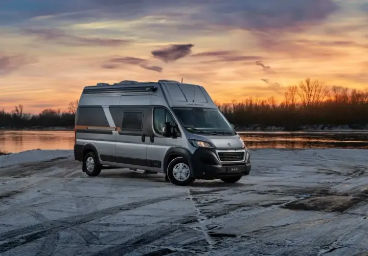 Srebrny kamper Globe-Traveller na tle zachodzącego słońca nad rzeką. Idealny, jaki kamper dla 2 osób na zimową podróż.