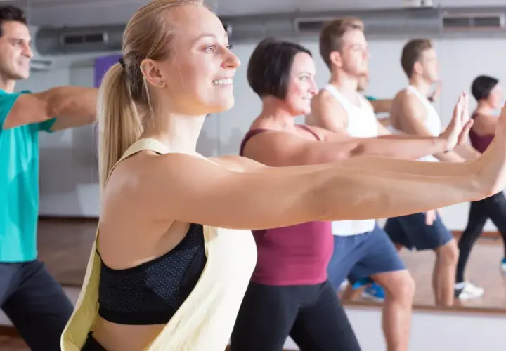 Ludzie na zajęciach zumbą, uśmiechnięci, wykonują ruchy. Zumbę co daje? Radość, energię i świetną sylwetkę!