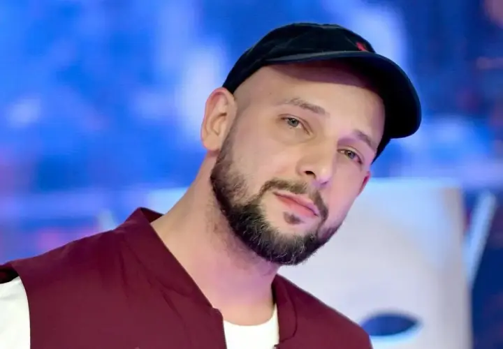 Maciej Pela, znany z ekranu, w czapce i kamizelce. Jego życiorys to historia sukcesu.